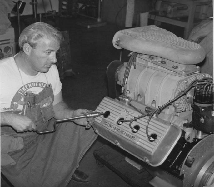 a mechanic working on a racing engine adjusting components