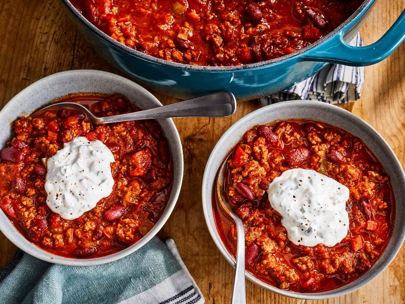 a high angle view of two bowls of the best damn chili each topped with a dollop of sour cream.