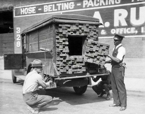 A federal agent inspecting a fake lumber truck full of liquor during prohibition, 1926.jpg